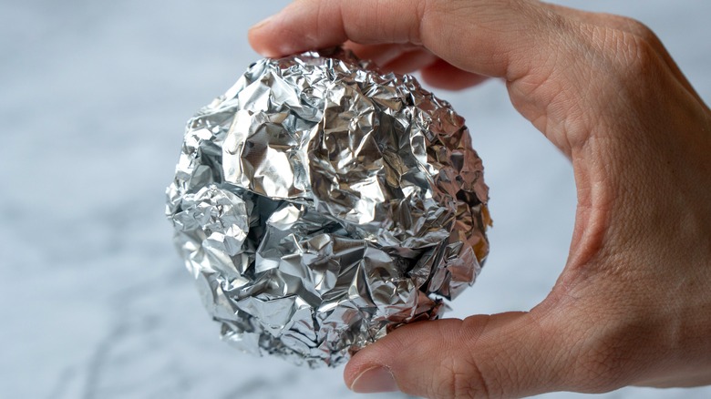 Hand holds ball of foil