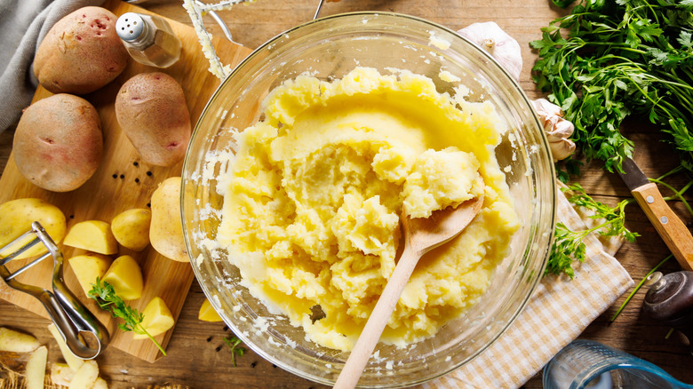 A bowl of mashed potatoes is in the process of being made.