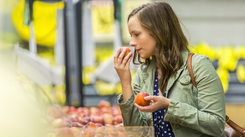 Person smelling peach at supermarket 