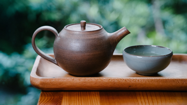 Rustic teapot and cup on wood in forest