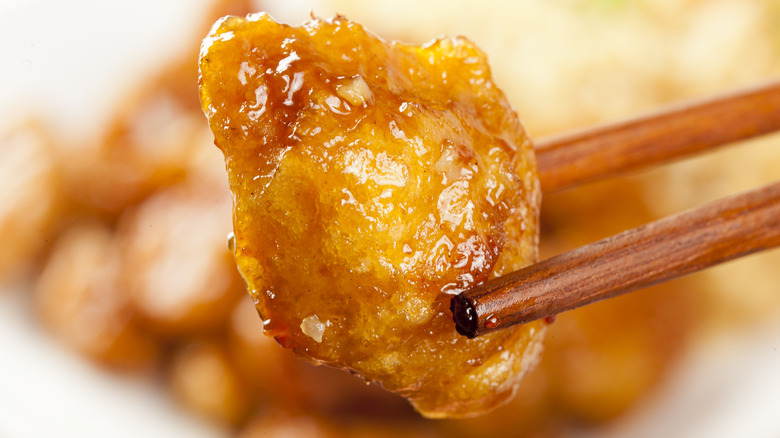 Orange chicken held by chopsticks