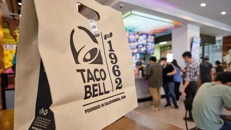 Taco Bell bag on a table inside busy restaurant