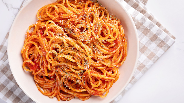 Spaghetti with cheese and herbs on checkered linen