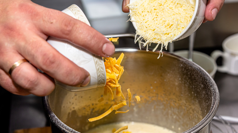 Adding grated cheese to a pot of sauce