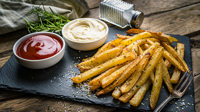 French fries on a slate with mayo and ketchup