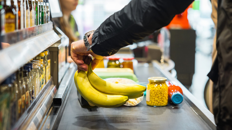 man placing bananas on checkout