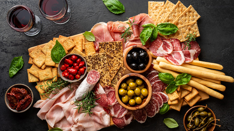 charcuterie board with wine on black background