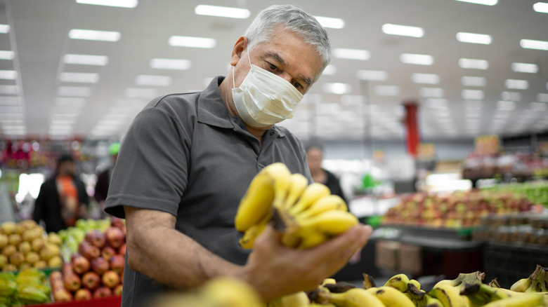 Masked man shopping for bananas