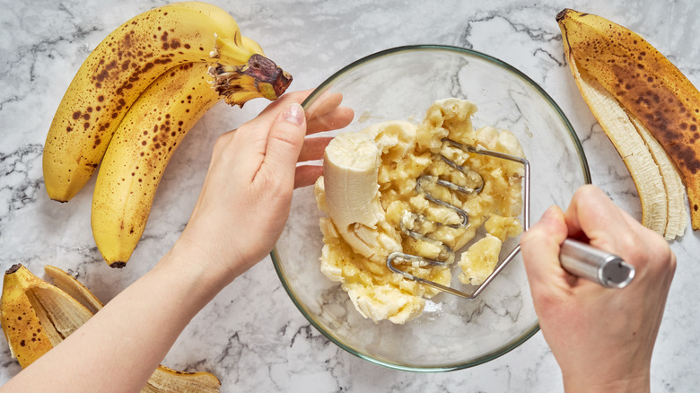 Person mashing bananas in bowl