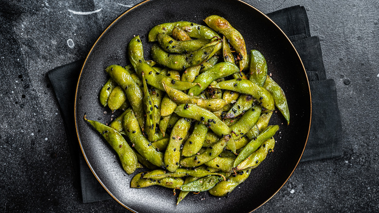 Crispy edamame on black plate