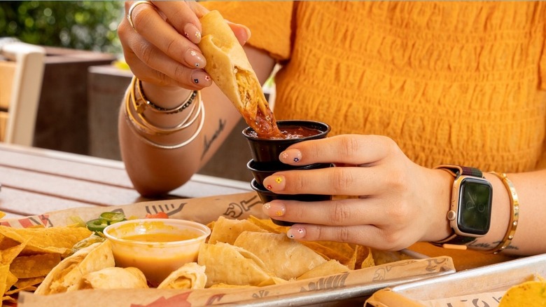 Dipping fried roll in hot sauce