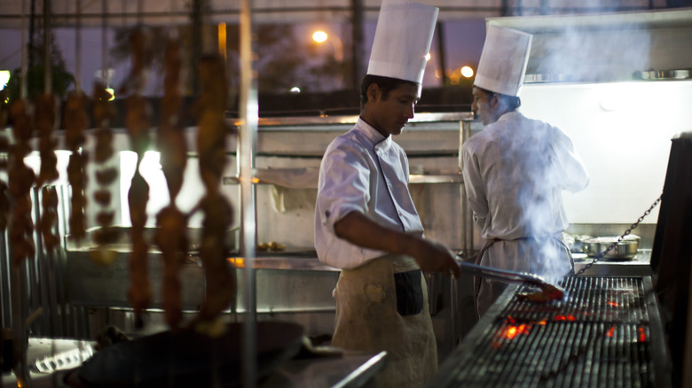 Chefs grilling tandoori skewers