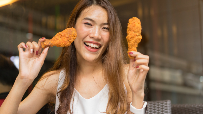 Happy woman eating fried chicken