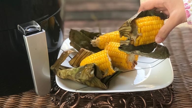 A plate of corn next to an air fryer