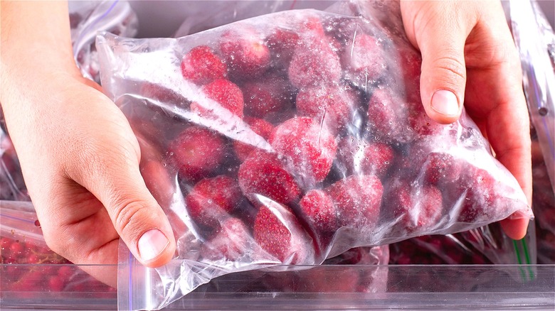 Hands holding bag of frozen strawberries 