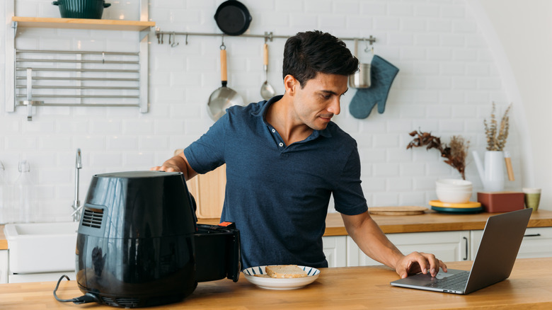 Man using air-fryer and laptop