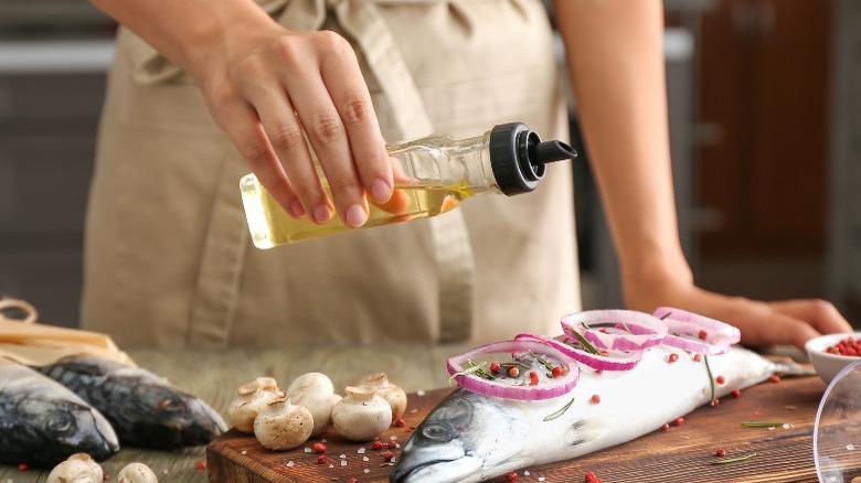 person pouring oil on raw fish