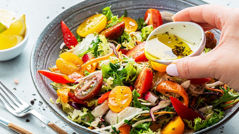 Putting dressing on leafy salad