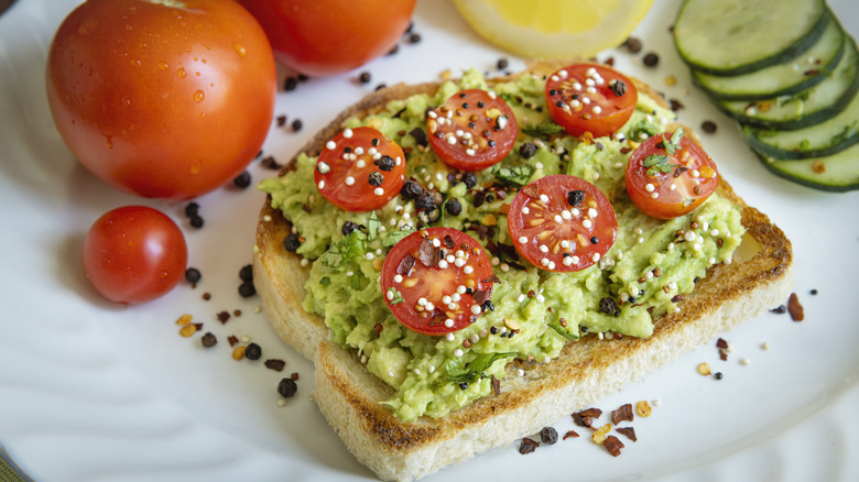 Open face toasted avocados sandwich topped with sliced tomatoes