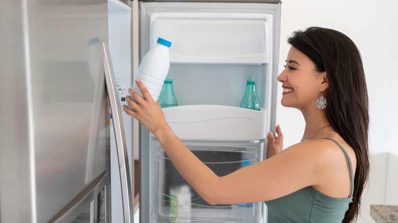 Woman putting milk in refrigerator