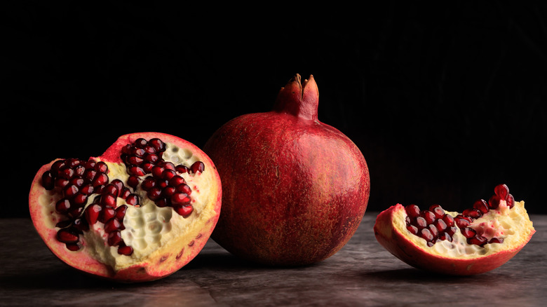 Whole and split pomegranates on dark background