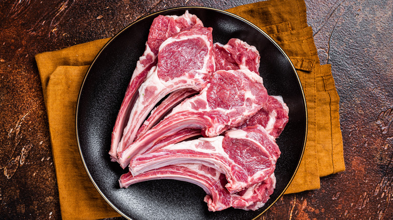 Raw lamb chops on a plate sitting atop a napkin