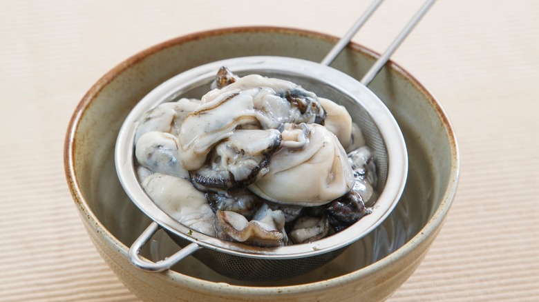 Raw oysters in a strainer