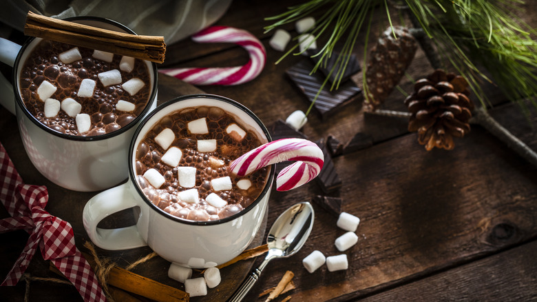 mugs of hot chocolate with candy canes and cinnamon sticks