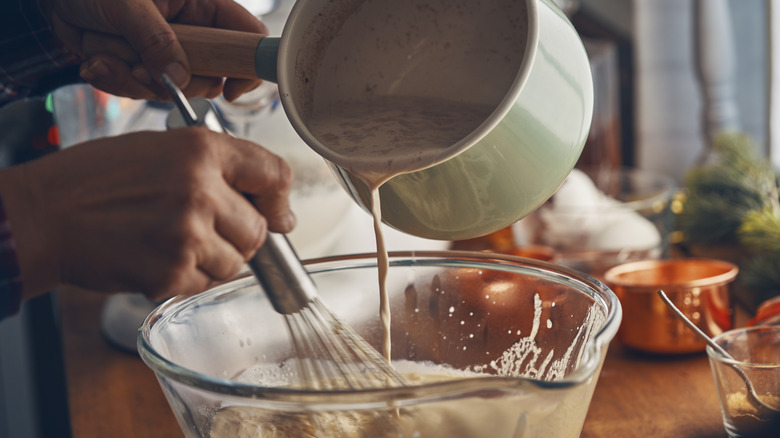 A person whisking ingredients to prepare eggnog.