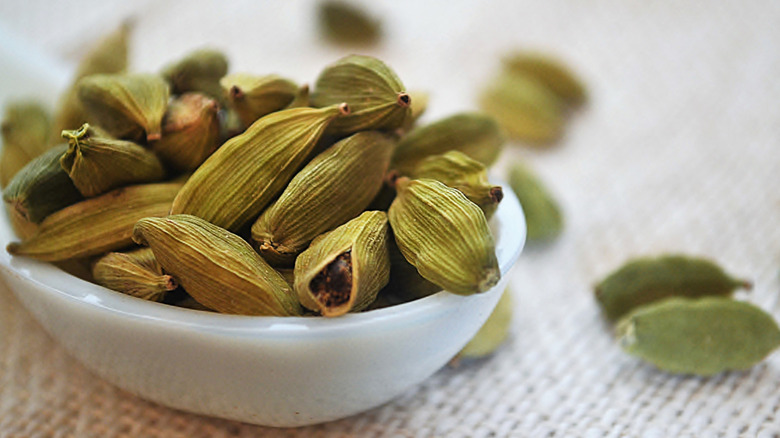 Cardamom pods in a milky white ceramic bowl.