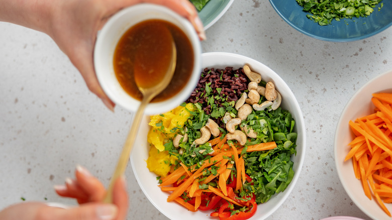 jar of dressing with spoon over salad bowl