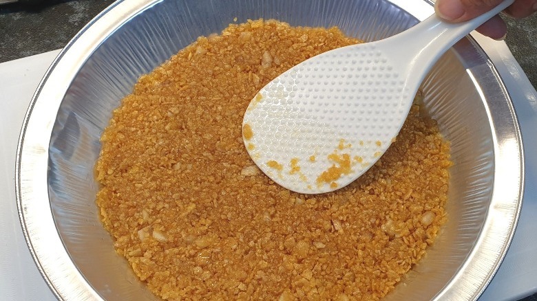 pressing cornflakes into pie tin