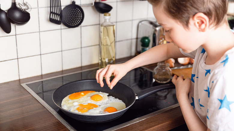 boy frying pan of eggs 