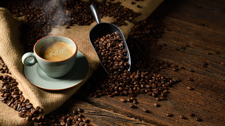 Cup of coffee near scoop of coffee beans