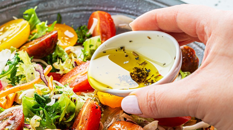 Pouring salad dressing on salad