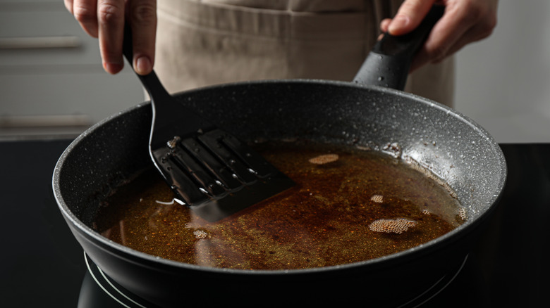 Person holding spatula in oil