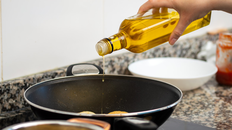 Person pouring oil in pan