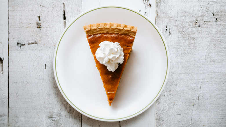 Pumpkin pie slice with whippped cream from above