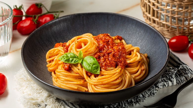 A bowl of spaghetti with sauce and basil