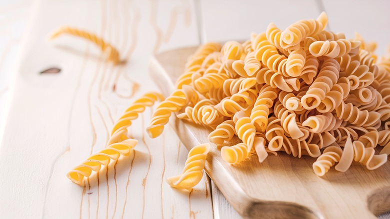 Uncooked fusilli pasta on a wooden board