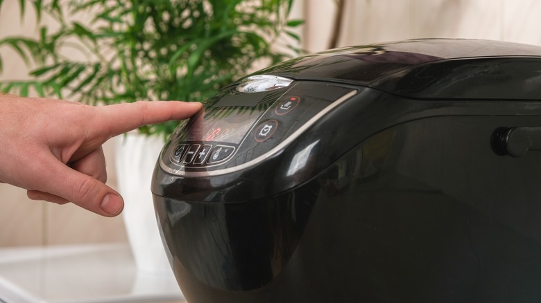 hand pressing button on slow cooker