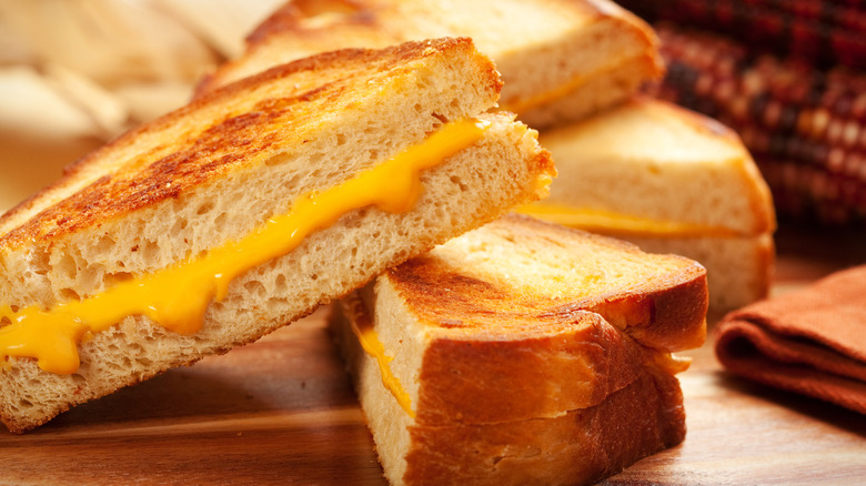 Two pieces of grilled cheese on a wooden platter