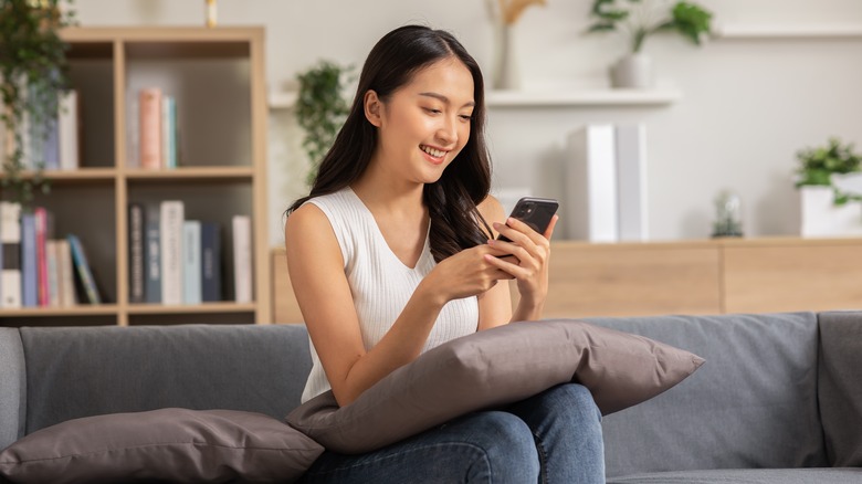 Woman at home on couch shopping on phone