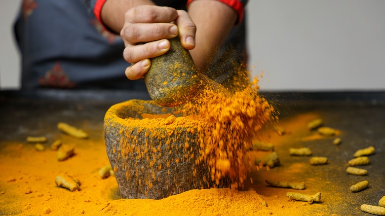 hands grinding turmeric root