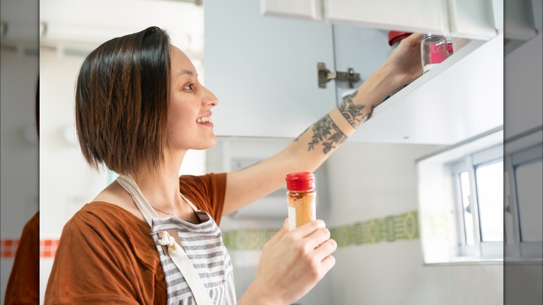 women pulling spice from cupboard