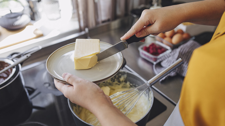 person cutting softened butter