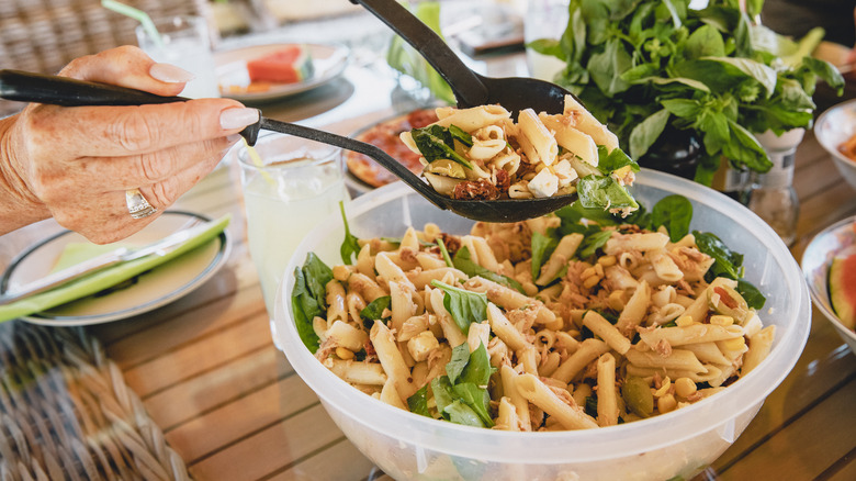 person serving pasta salad