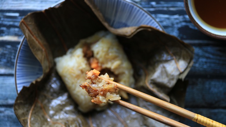 Lo mai kai, with a pinch of rice and meat held by chopsticks.