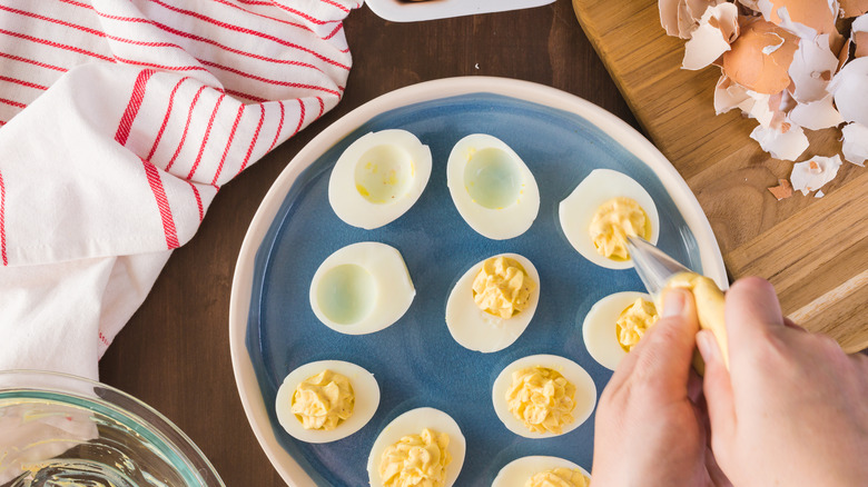 deviled eggs being made on plate on cutting board