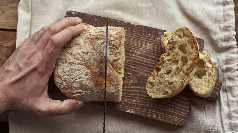 Person slicing ciabatta bread